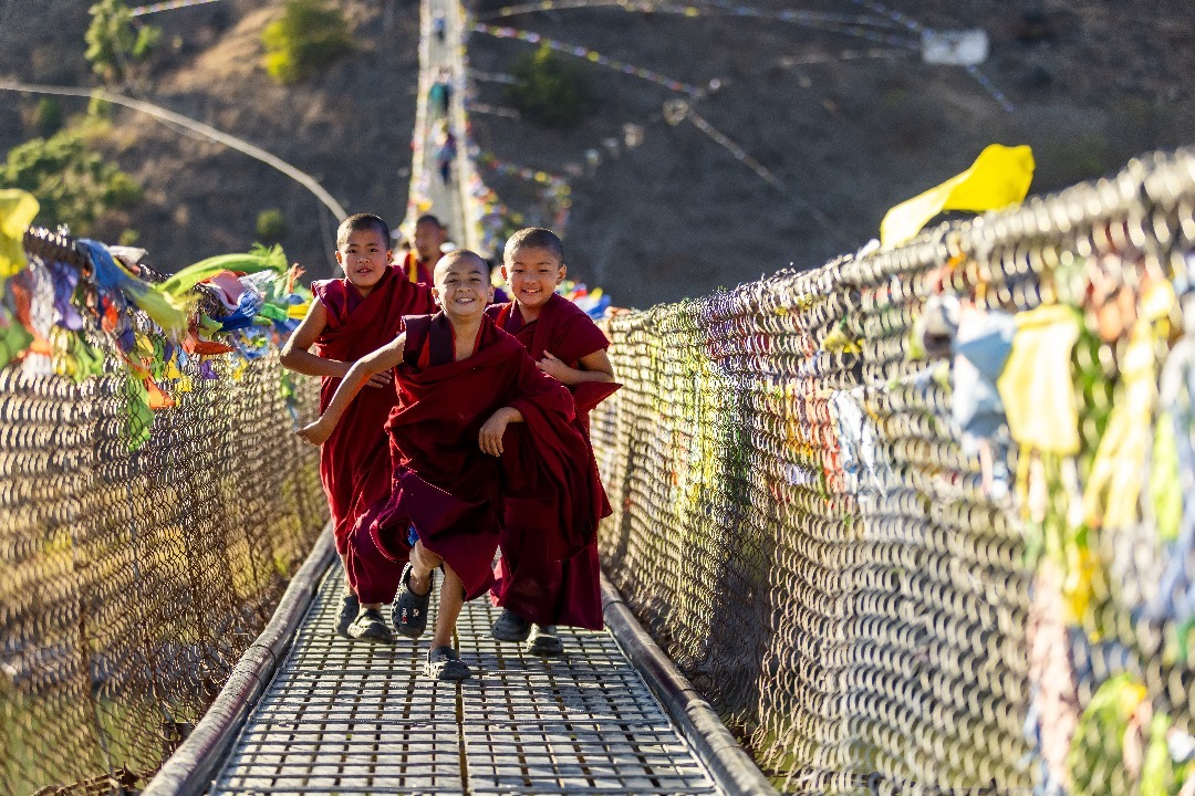 Joyous children in Bhutan on suspension bridge